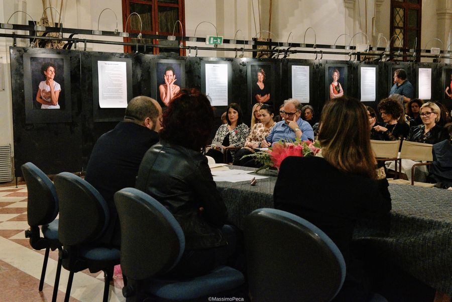 Il pubblico osserva i ritratti esposti lungo le pareti della sala espositiva