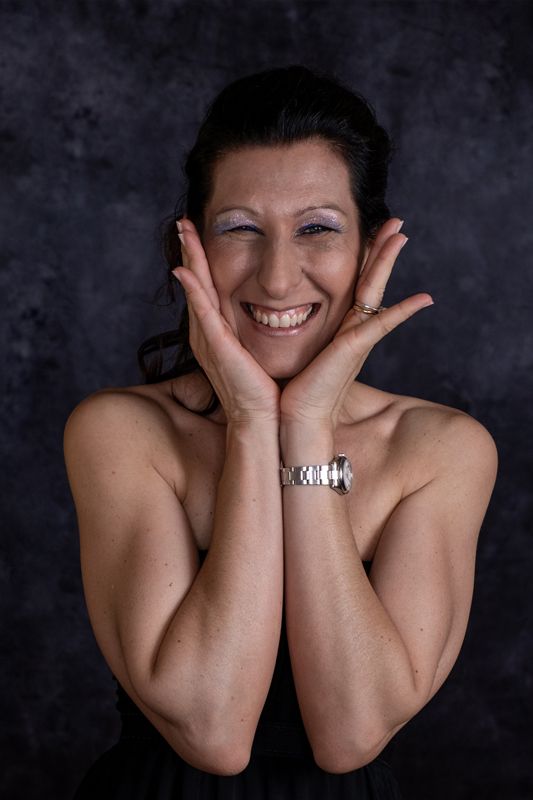 Ritratto in studio di una donna dell’associazione con le mani sul viso